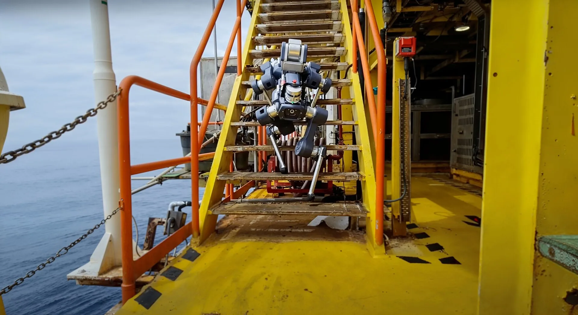 ANYmal X descending metal stairs on an offshore platform